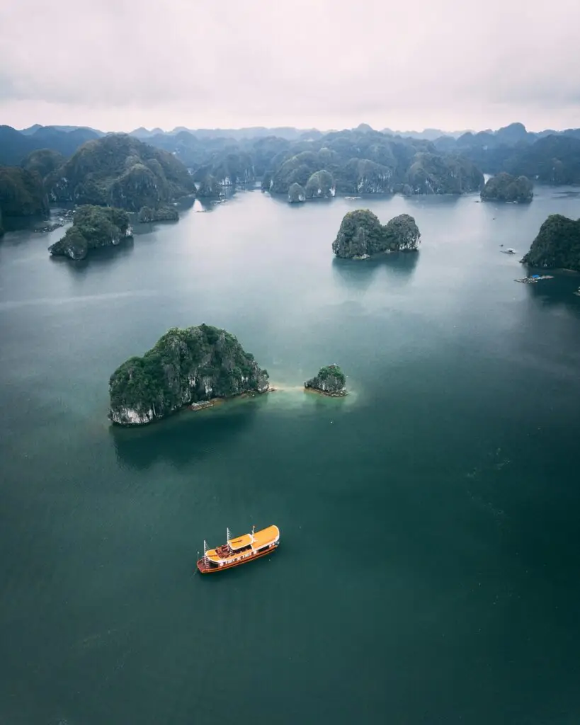 A stunning aerial view of Ha Long Bay, Vietnam with a boat cruising between limestone islands.