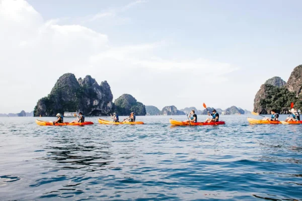 Group kayaking on tranquil waters with stunning rock formations and clear skies.